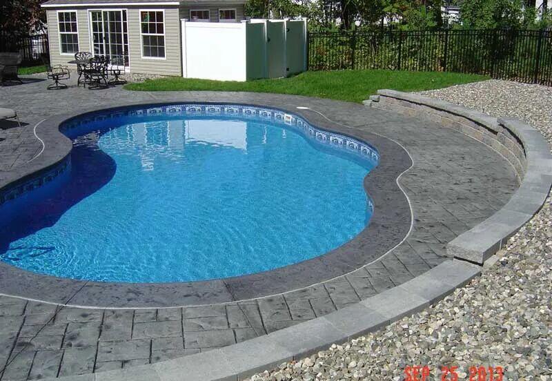 Freeform pool with stamped concrete deck and block wall