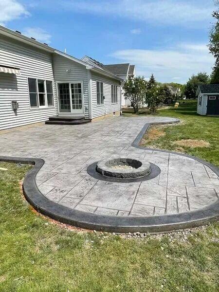 Curved stamped patio with dark border and circular fire pit inset
