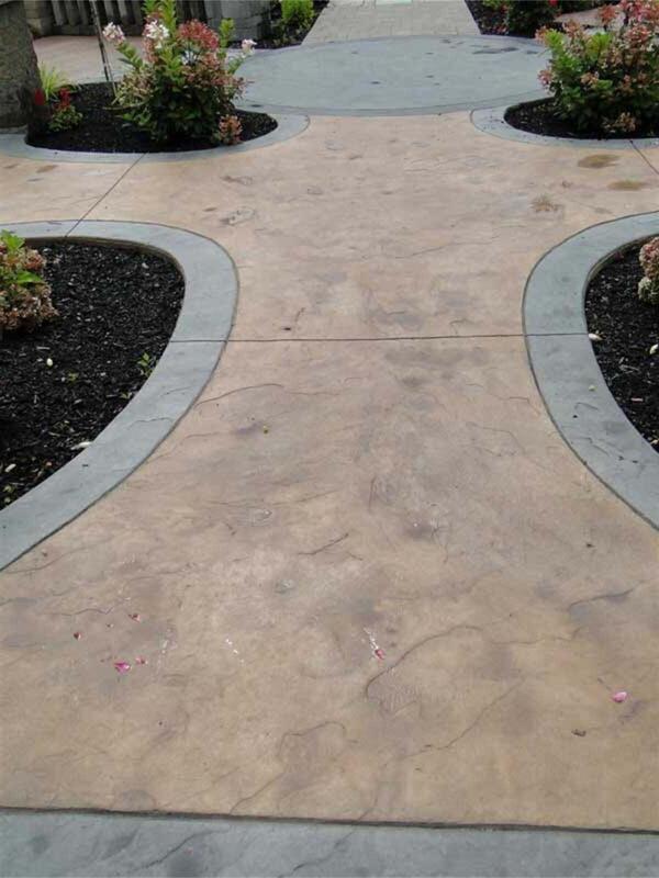 Tan stamped walkway with charcoal borders and curved planting beds