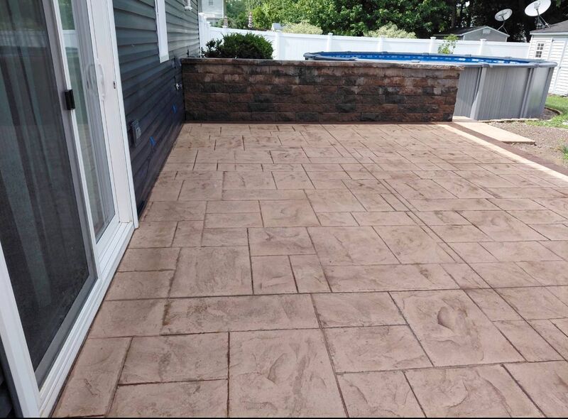 Tan ashlar stamped patio block retaining wall above ground pool