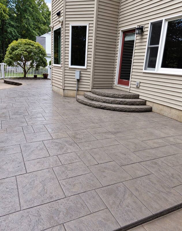 Gray ashlar stamped patio curved rock face steps red door