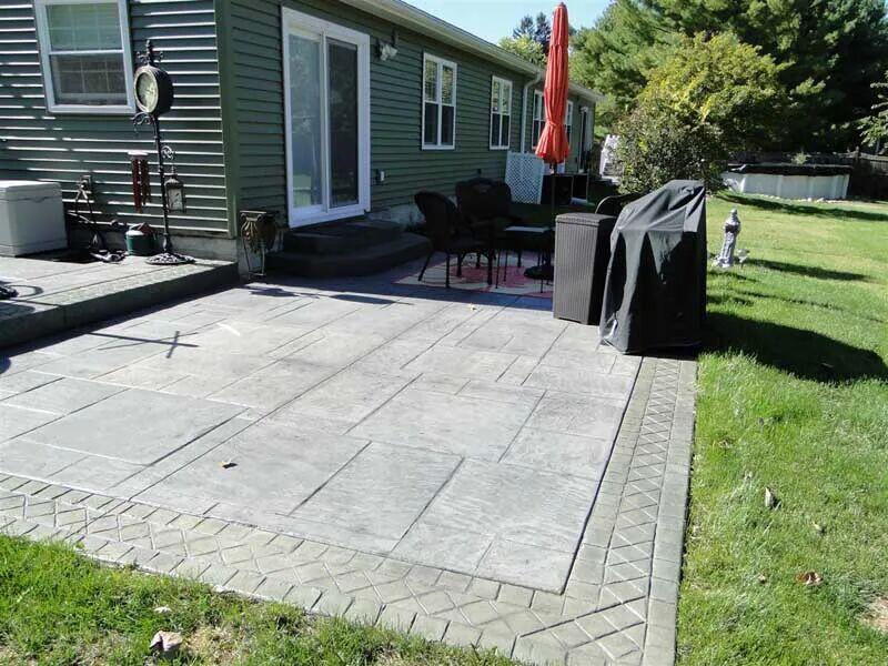 Stamped patio with paver border behind green house