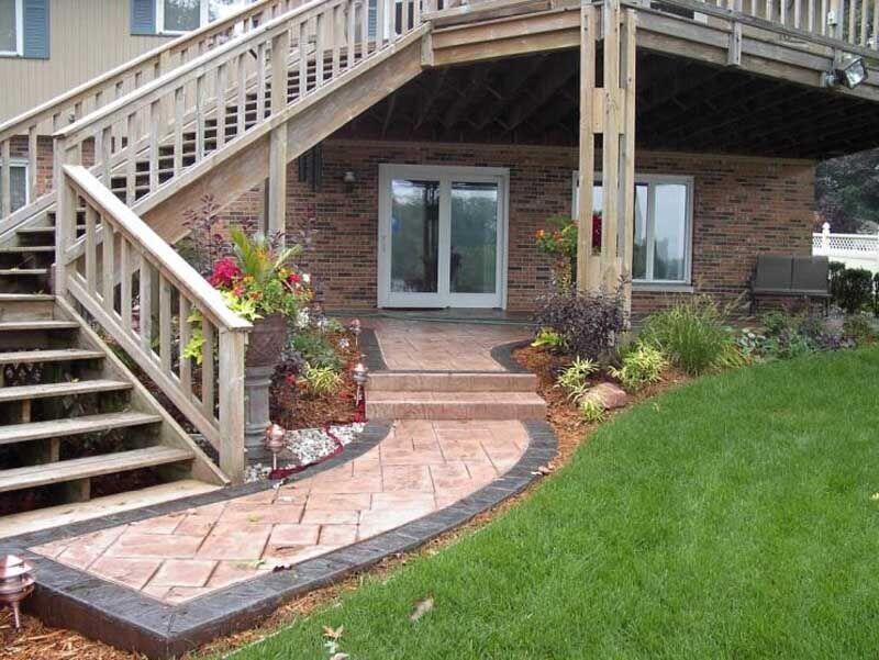 Stamped brick-pattern walkway under deck with plantings