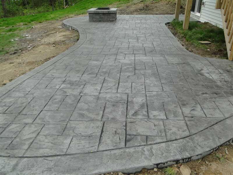 Gray stamped ashlar patio with fire pit under deck fresh pour