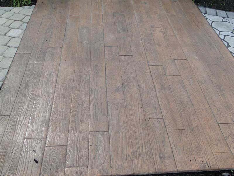 Wood-plank stamped concrete closeup with paver border