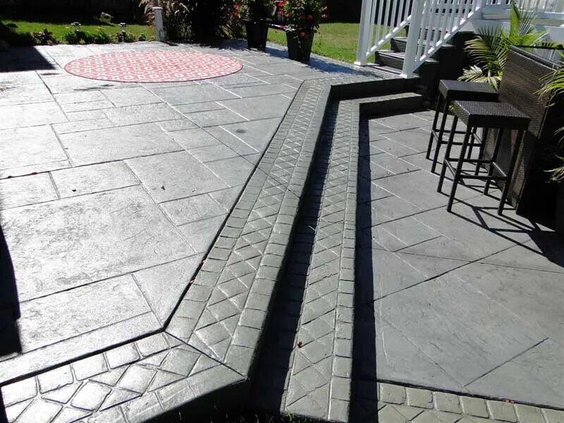 Two-level charcoal stamped ashlar patio with cobble borders and step